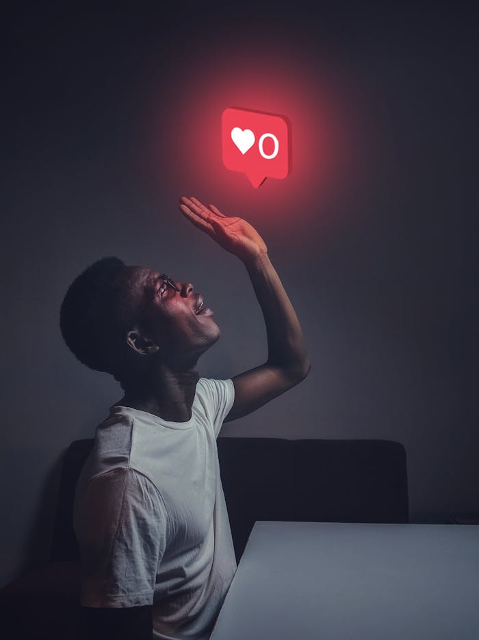 pexels-photo-3314294 A man sits indoors reaching towards a glowing social media notification icon.