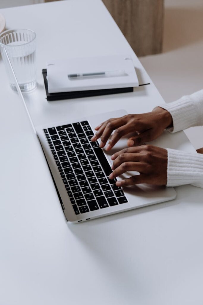 pexels-photo-5076523 A woman typing on a laptop at a modern home office desk indoors.